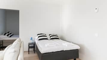 A modern bedroom with a bed, bedside table, and a desk area.