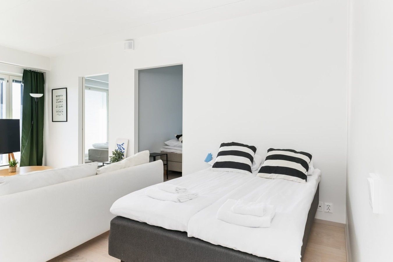 A modern hotel room with a bed, a sofa, a desk, and a window.