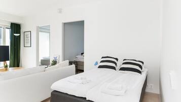 A modern hotel room with a bed, a sofa, a desk, and a window.