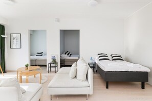 Un saló modern i minimalista amb un sofà, un llit i una taula petita.