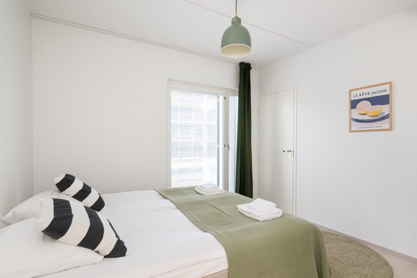 Un dormitorio con una cama, una ventana con persianas, una puerta y un cuadro colgado en la pared.