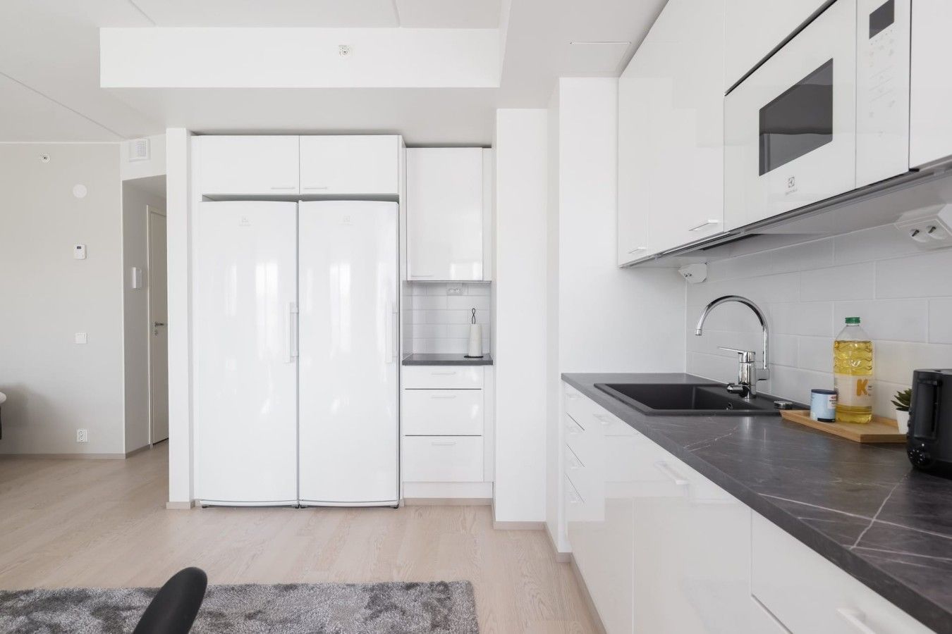 Una cocina moderna con armarios blancos, encimera negra y pileta de acero inoxidable.