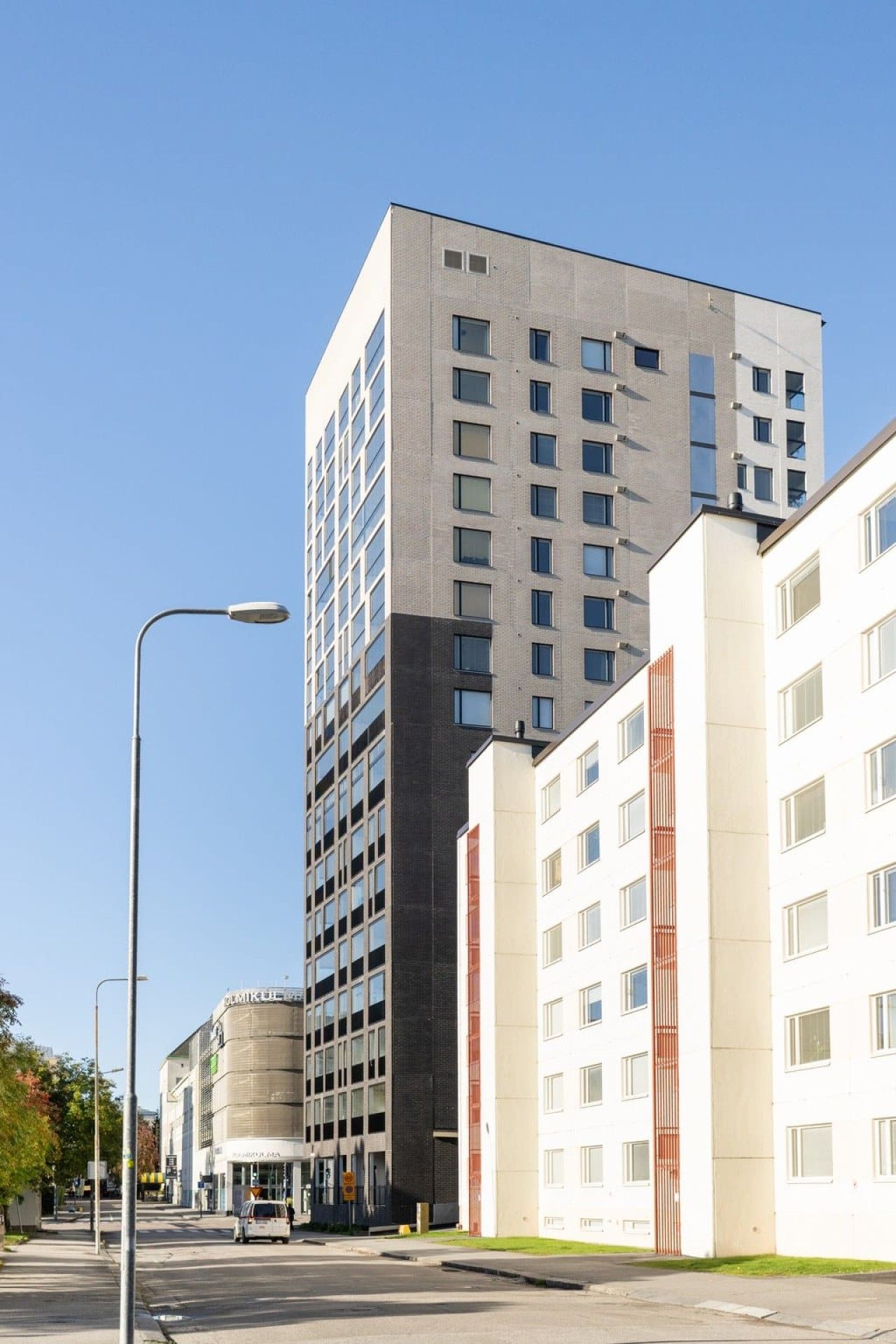 Un edificio moderno de varios pisos, una calle al frente y cielo despejado.