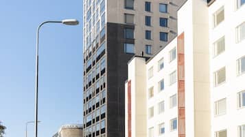 Un edificio moderno de varios pisos, una calle al frente y cielo despejado.