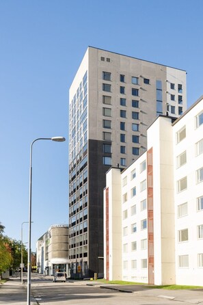 Un edificio moderno de varios pisos, una calle al frente y cielo despejado.
