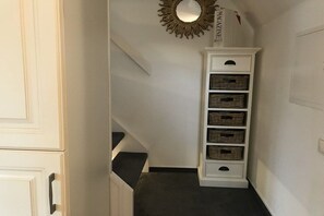 A hallway with a white cabinet, a mirror, and wicker baskets. - "Syltperle" in the Sölring-Hüs (Sylt\/Rantum)