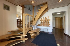 Un escalier en bois avec un banc au bas, un radiateur et une porte donnant sur une autre pièce.