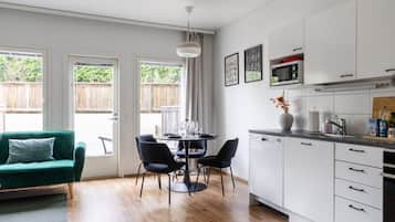 Eine moderne Küche mit weißen Schränken, einem Esstisch mit Stühlen und einem grünen Sofa.