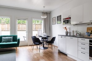 Eine moderne Küche mit weißen Schränken, einem Esstisch mit Stühlen und einem grünen Sofa.