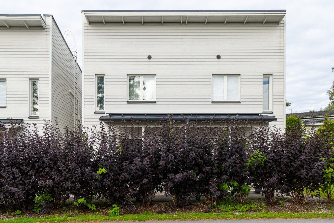 Ein zweistöckiges Wohnhaus mit flachem Dach und einer überdachten Veranda.