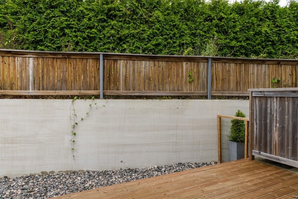 Eine Holzterrasse mit einer Betonmauer und einem Metallzaun.