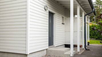 A white building with a dark door, a porch with a railing, and a small step leading to the entrance.