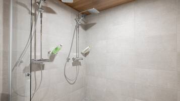 A shower area with a glass door, a wooden ceiling, and tiled walls.
