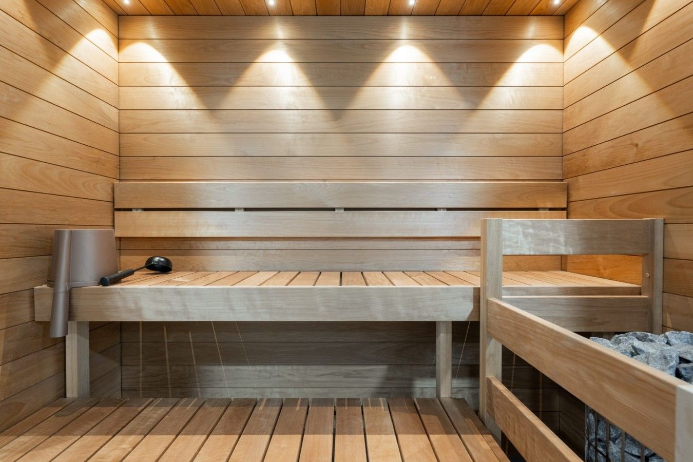 Una sauna con paredes y bancos de madera, un calentador para los bancos y una pequeña mesa.