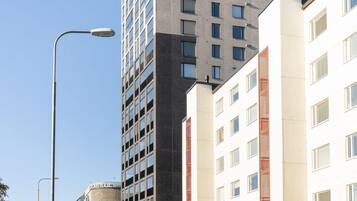 Un edificio moderno de varios pisos, una calle al frente y cielo despejado.