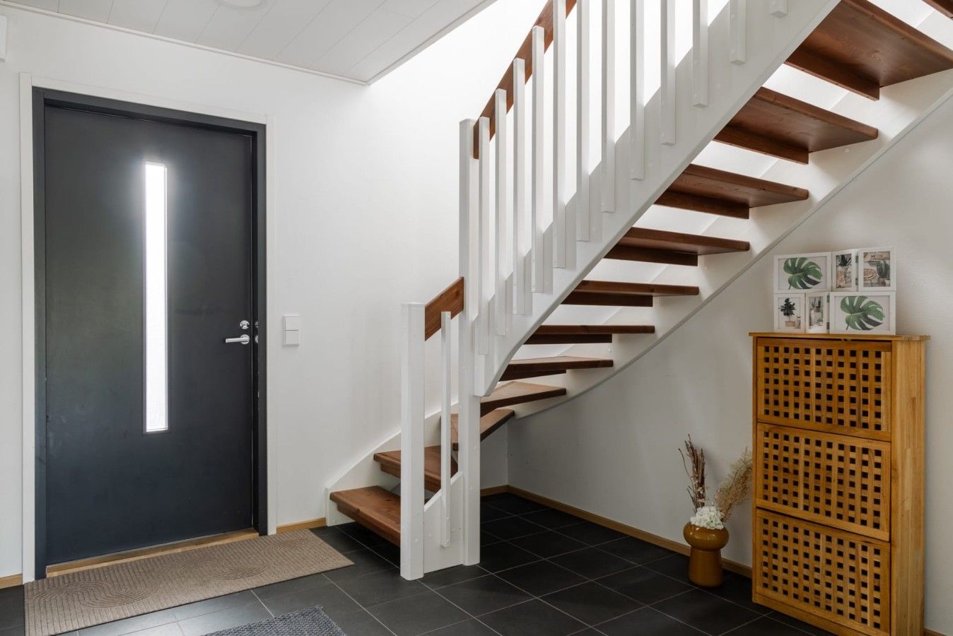 A modern staircase with white railings and wooden steps leading to a dark door.