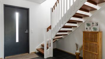 A modern staircase with white railings and wooden steps leading to a dark door.