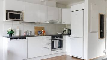 A modern kitchen with white cabinetry, a built-in microwave, a coffee maker, and a dishwasher.