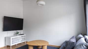 A modern living room with a flat-screen TV, a wooden coffee table, a white entertainment unit, and a grey sofa.