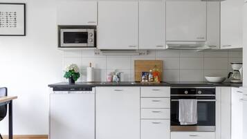 A modern kitchen with white cabinetry, a built-in microwave, a dishwasher, and an oven.