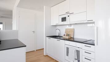 Una cocina moderna con armarios blancos, encimera negra y tabla de cortar de madera.