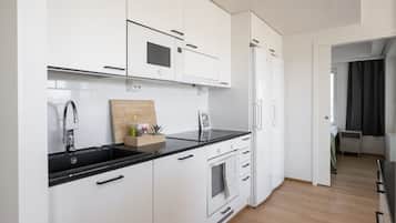 Una cocina moderna con armarios blancos, encimera negra y horno empotrado.