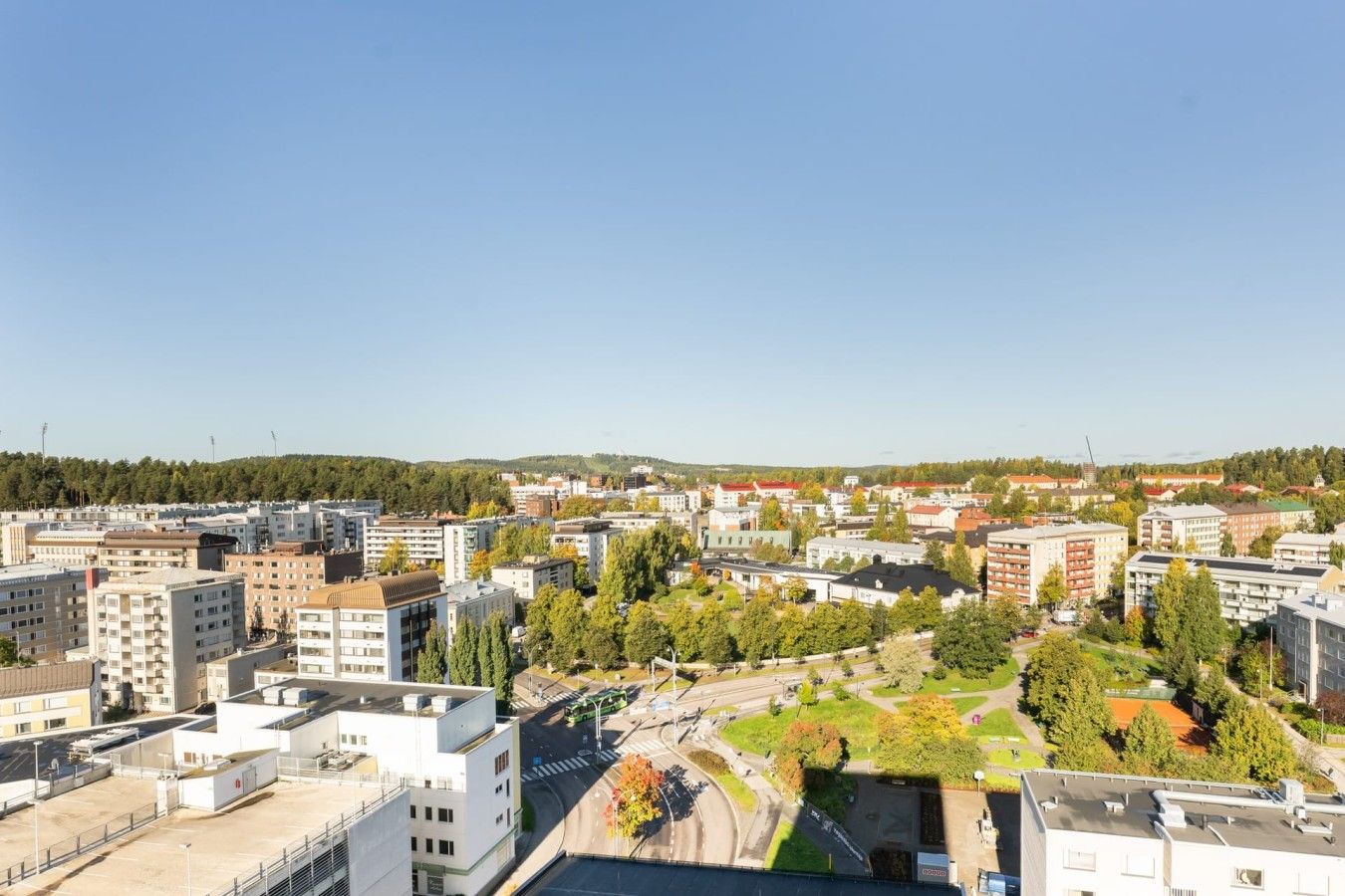 Kaupunkikuva, jossa on näkyvillä erilaisia rakennuksia, teitä ja kirkas taivas.