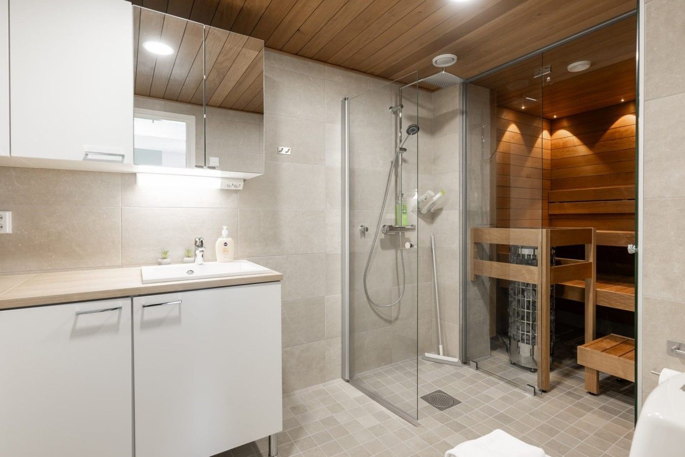 Un bagno moderno con doccia vetro, mobile contenitore in legno e uno specchio grande.