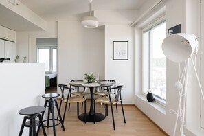 Moderni ruokailutila, jossa on pyöreä pöytä, mustat tuolit ja katosta roikkuva valaisin.