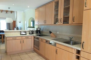 Eine Küche mit Holzausstattung, einer Arbeitsplatte aus Granit, Edelstahlgeräten und einem Messerblock.