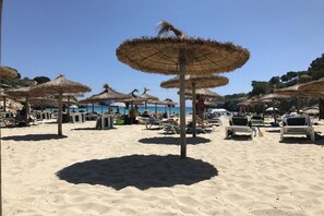 Ein Strand mit Reetsonnenstühlen und Liegestühlen.
