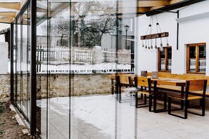 A wooden bench and table set in a snowy outdoor area with a glass wall reflecting the scene. - Jura Chalet Eggersberg (Obereggersberg)