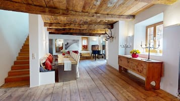 Ein rustikales Interieur mit einer Holztreppe, einem Essbereich und einem Flur, der zu einem Raum mit einem großen Fenster führt.