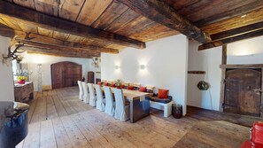 Ein rustikaler Essbereich mit einem langen Holztisch, Stühlen und einer Holzzieldecke.