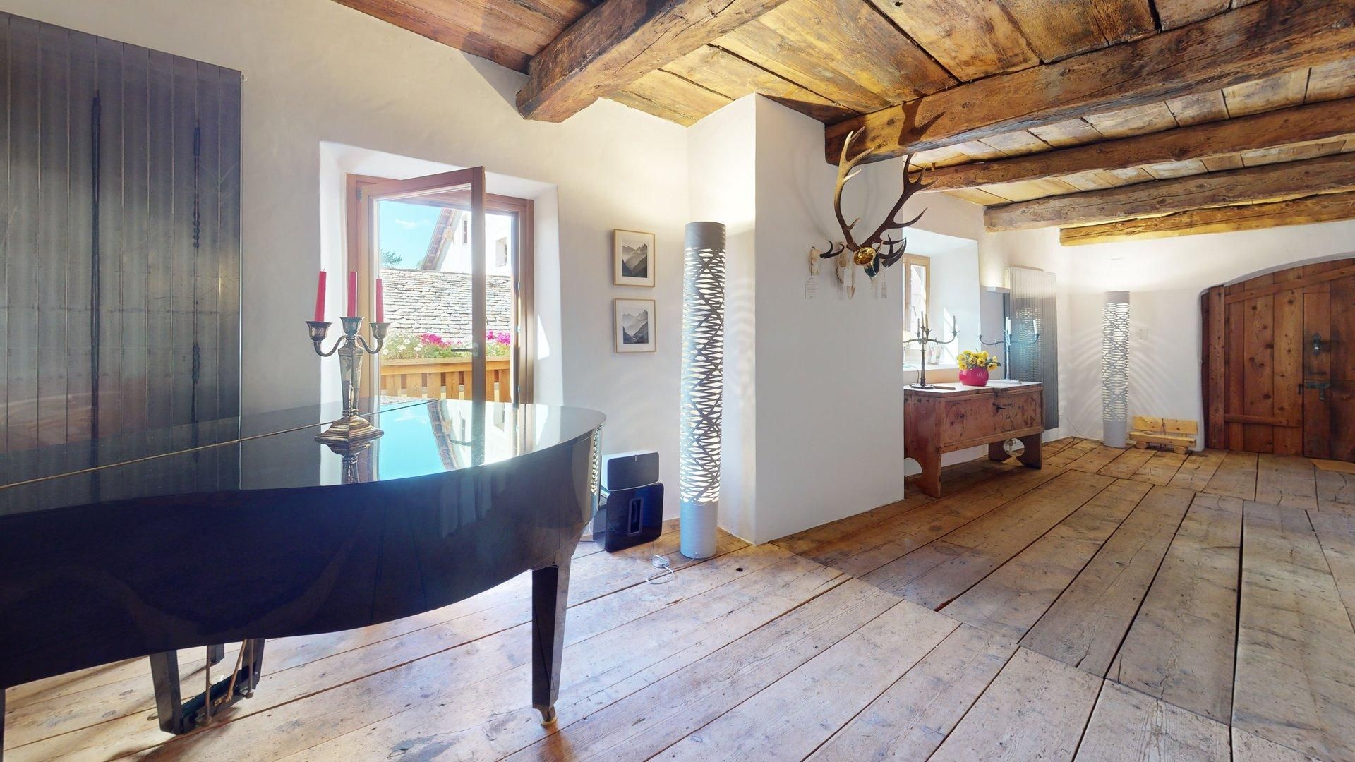 Ein geräumiger Raum mit einem großen Holztisch, Holzboden und rustikaler Decke.