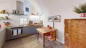 Eine kompakte Küche mit Backofen, einem Esstisch mit Stühlen und einem Holzkasten.