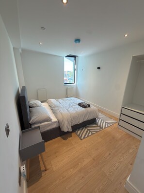 A modern bedroom with a bed, bedside tables, a window, and a view of the city. - Modern 3 Bedroom Flat on Eltham High Street| 7 mins from the Station! (London)