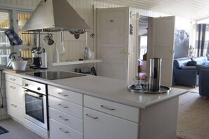A kitchen with a built-in oven, a large island with a sink, and a hanging pot rack. - Holiday home with 4 bedrooms (Egernsund)