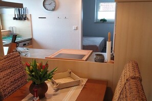 Un espacio habitable compacto con kitchenette, comedor con mesa y sillas, cama y ventana con vistas.