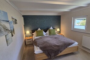 A bedroom with a bed, bedside lamps, a window, and artwork on the wall. - Holiday home in Cuxhaven with swimming pool (Cuxhaven)