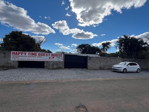 A guest house with a signboard advertising 24-hour accommodation, a gated entrance, and a parked car. - Happy Time Guest House  (Phalaborwa)