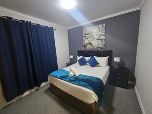 A hotel room with a bed, a nightstand, a lamp, and a painting on the wall. - Sandton Westpoint Luxury Apartments 158 (Sandton)