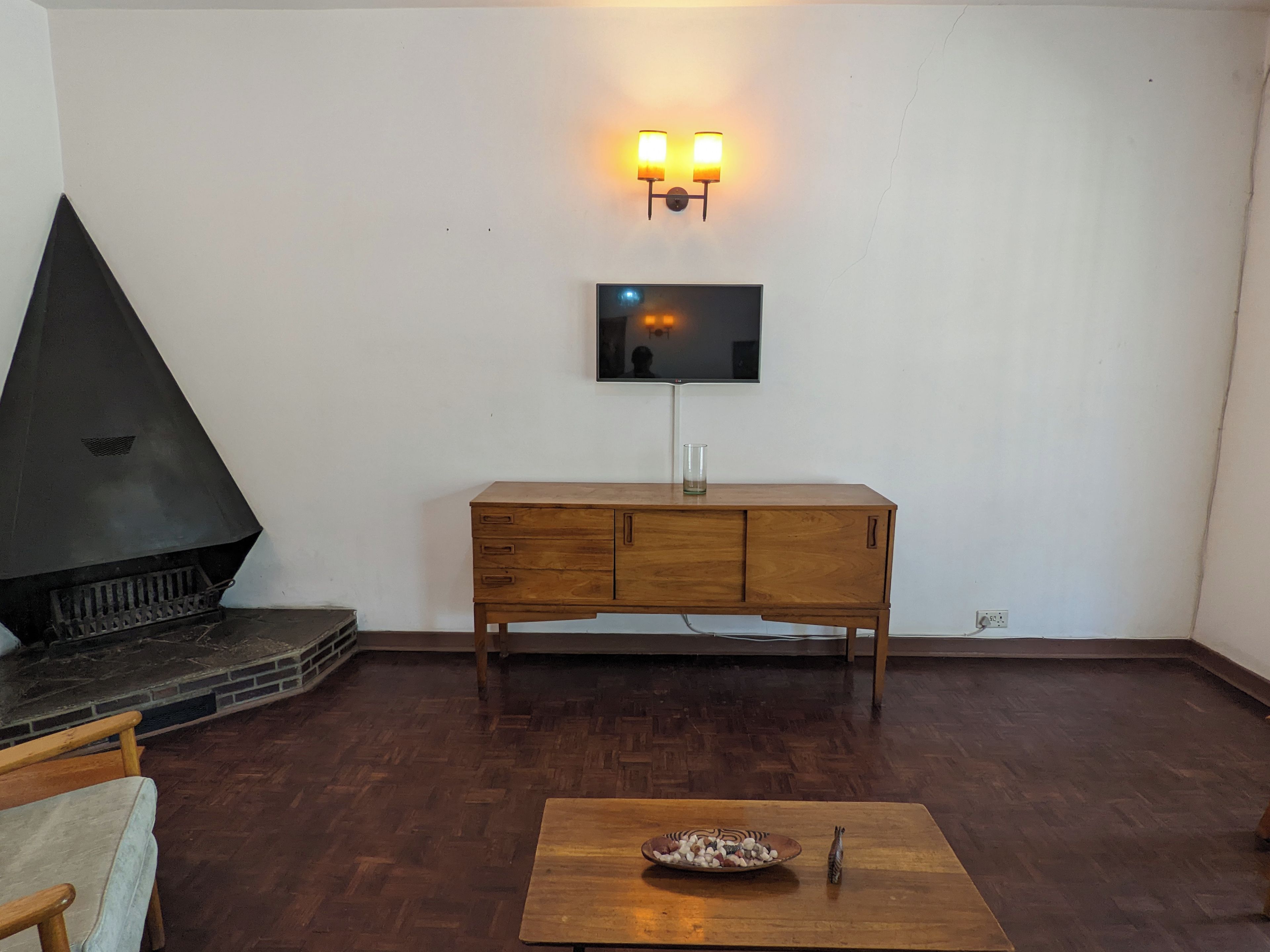 Una sala de estar con chimenea, televisor montado en la pared y una mesa de centro de madera.