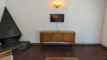 Una sala de estar con chimenea, televisor montado en la pared y una mesa de centro de madera.
