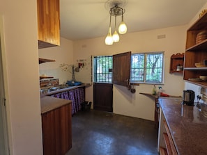 A kitchen with wooden cabinets, a sink, and a window with bars.