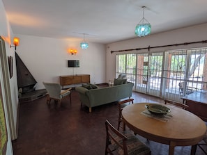 Una sala de estar con chimenea, sofá, televisión y mesa de comedor.