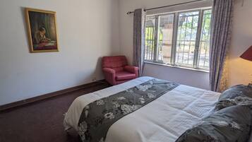 Une chambre à coucher avec un lit, une chaise, une fenêtre et un tableau accroché au mur.