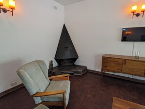 Ein Wohnzimmer mit Kamin, Wandfernseher und Holzschrank.