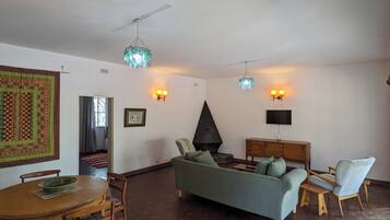 A living room with a sofa, chairs, a dining table, a fireplace, and wall-mounted lights.