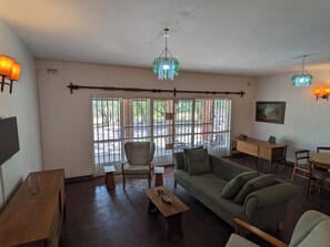 A spacious living area with a sofa, chairs, a coffee table, a TV, and a dining table.
